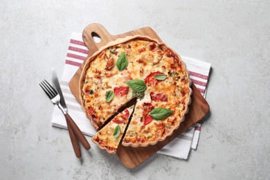 Photo of Tasty quiche with tomatoes, basil and cheese served on light textured table, flat lay