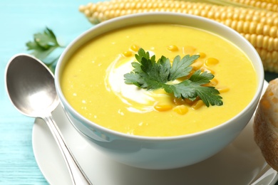 Photo of Delicious creamy corn soup served on turquoise wooden table