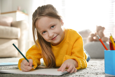 Little girl drawing on floor at home