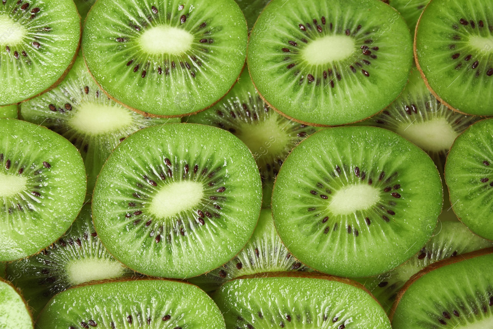 Photo of Sliced fresh ripe kiwis as background, top view