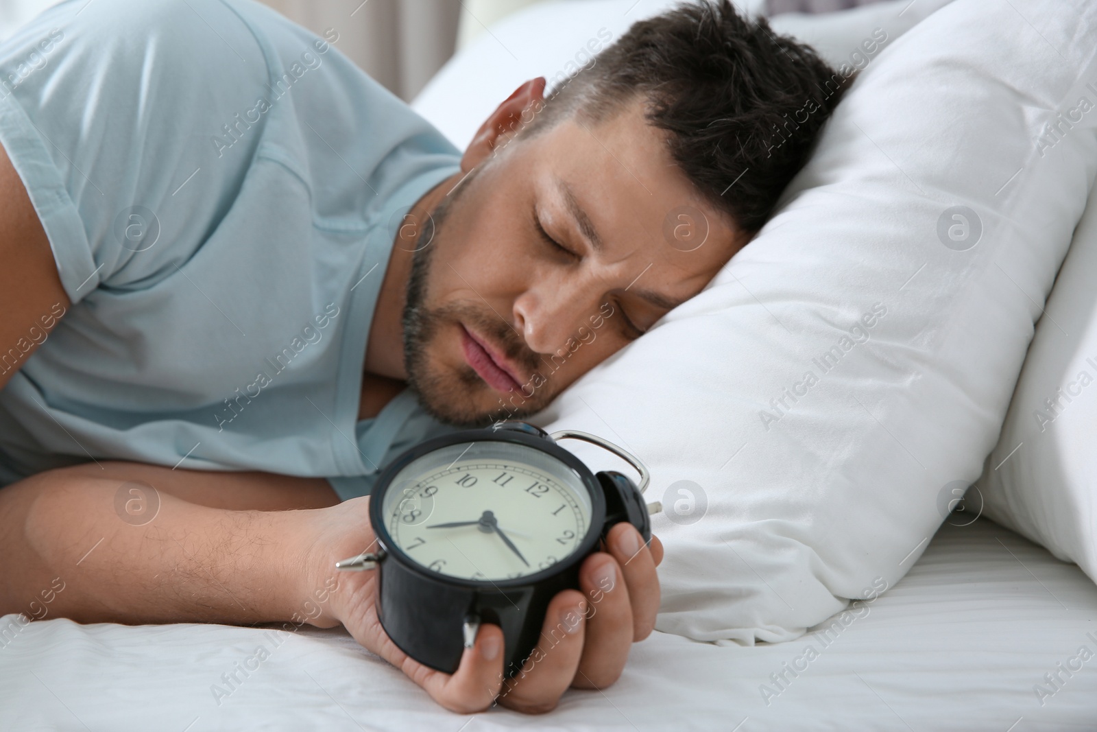 Photo of Man sleeping with alarm clock at home in morning