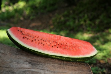 Photo of Slice of delicious ripe watermelon on log outdoors