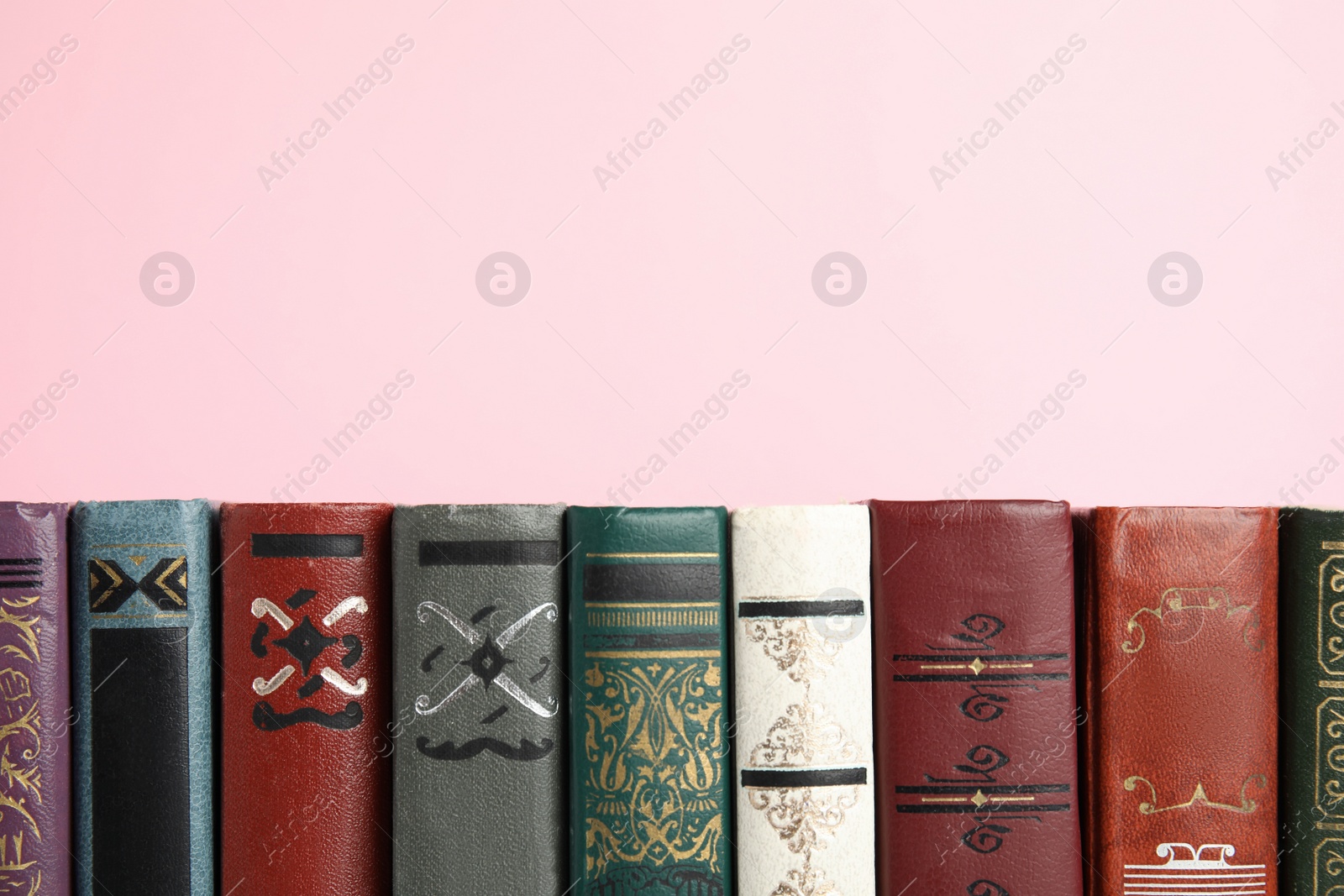 Photo of Collection of old books on pink background, space for text