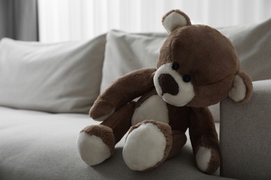Photo of Cute lonely teddy bear on sofa in room