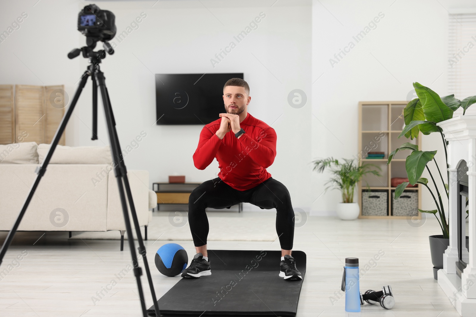 Photo of Trainer recording workout on camera at home