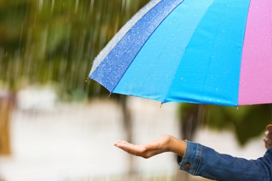 Photo of Woman with bright umbrella under rain on street, closeup