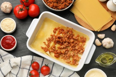 Flat lay composition with products for cooking lasagna on dark textured table