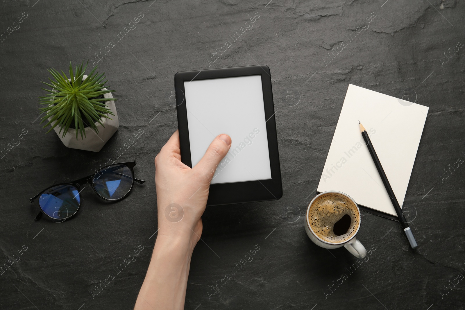 Photo of Woman using e-book reader at black table, top view