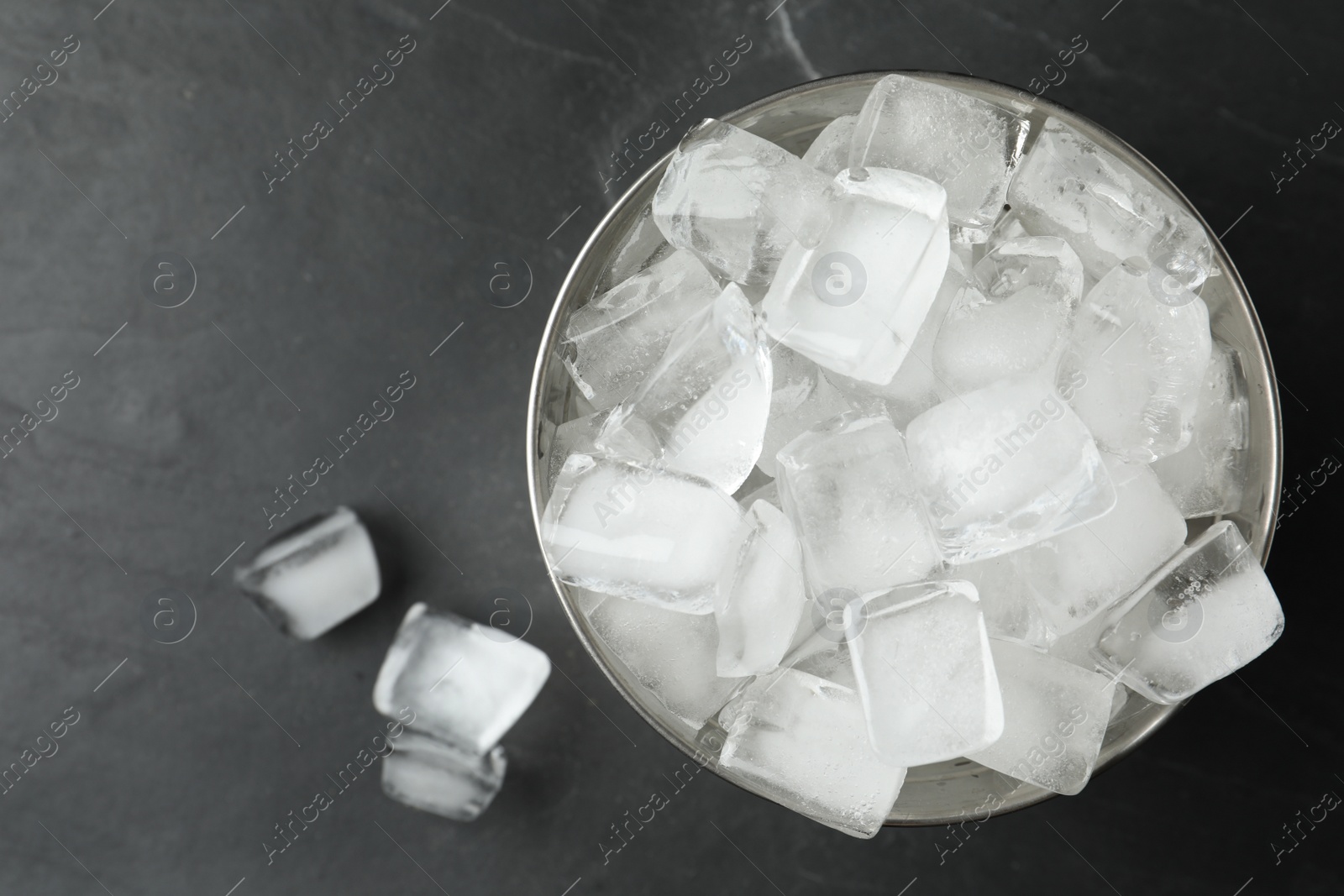 Photo of Metal bucket with ice cubes on grey background, flat lay