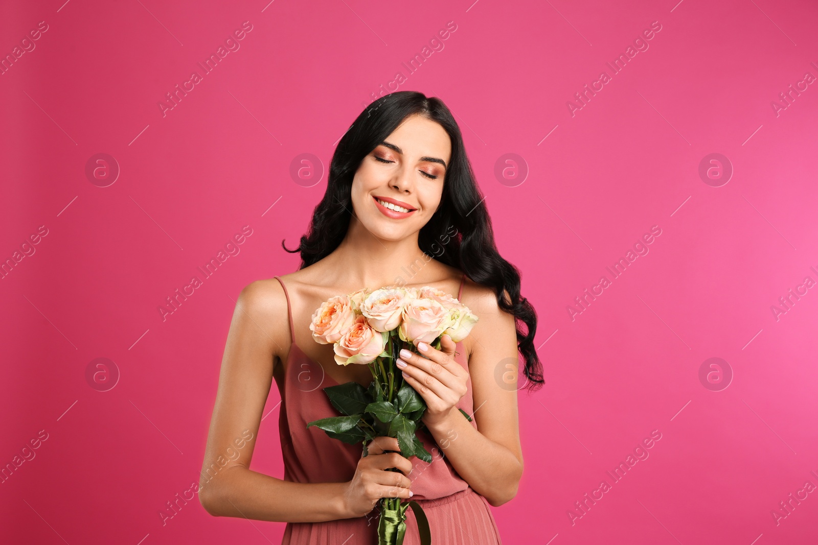 Photo of Portrait of smiling woman with beautiful bouquet on pink background