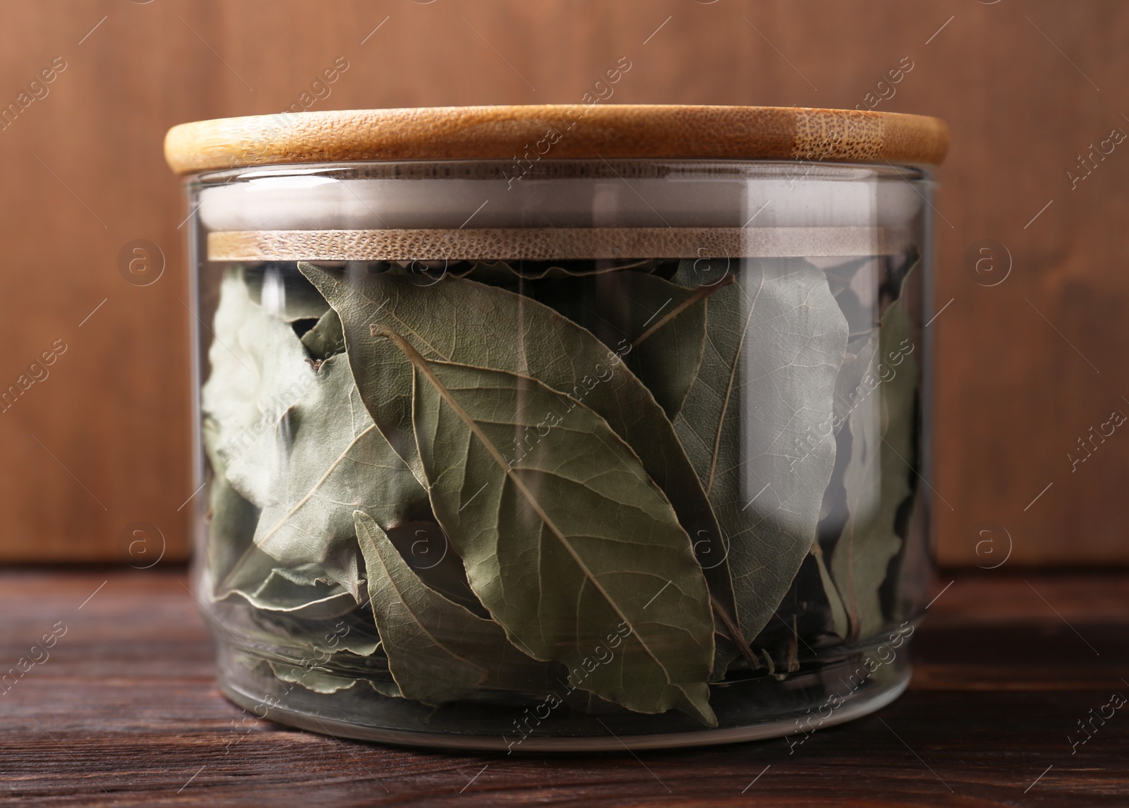 Photo of Bay leaves in glass jar on wooden table