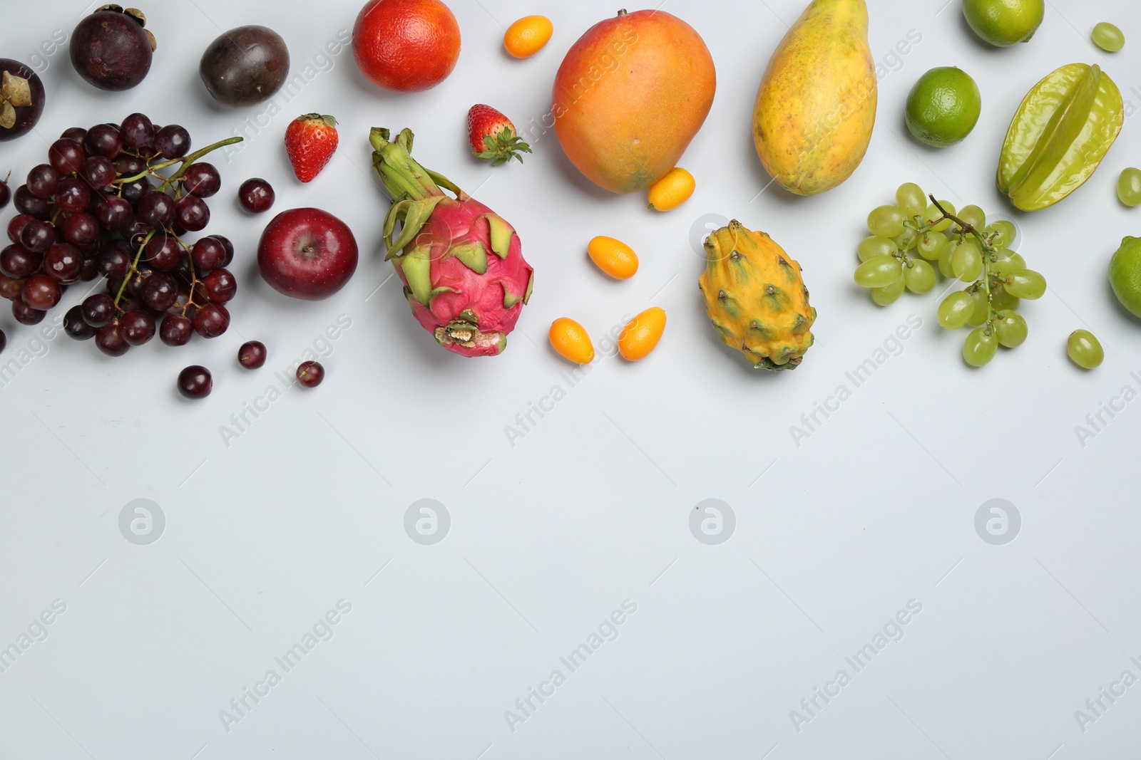 Photo of Many different delicious exotic fruits on light background, flat lay. Space for text