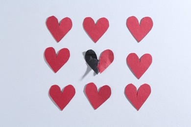 Halves of torn paper heart and red decorative hearts on gray background, flat lay. Breakup concept