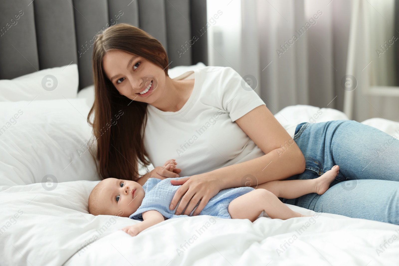 Photo of Mother with her cute baby on bed indoors