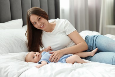 Photo of Mother with her cute baby on bed indoors