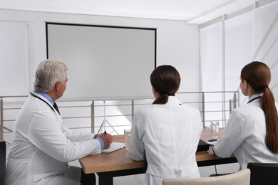 Team of doctors using video projector during conference indoors