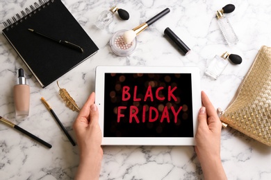 Woman shopping online using tablet at white marble table, top view. Black Friday Sale