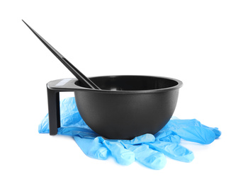 Photo of Bowl with hair dye, brush and rubber gloves on white background