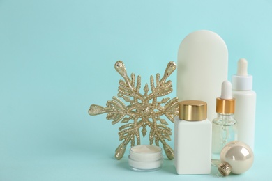 Photo of Beautiful composition with cosmetic products on cyan background, space for text. Winter care