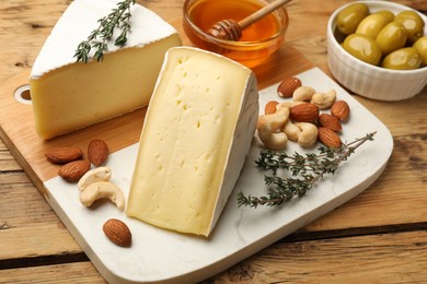 Tasty Camembert cheese with thyme, honey and nuts on wooden table, closeup