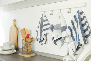 Photo of Different kitchen towels hanging on hook rack indoors