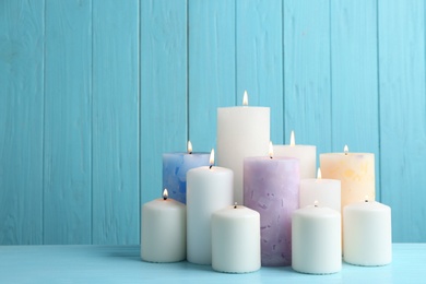 Set of burning candles on table against light blue wooden background. Space for text