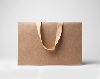 Paper shopping bag with comfortable handles on white background. Mockup for design