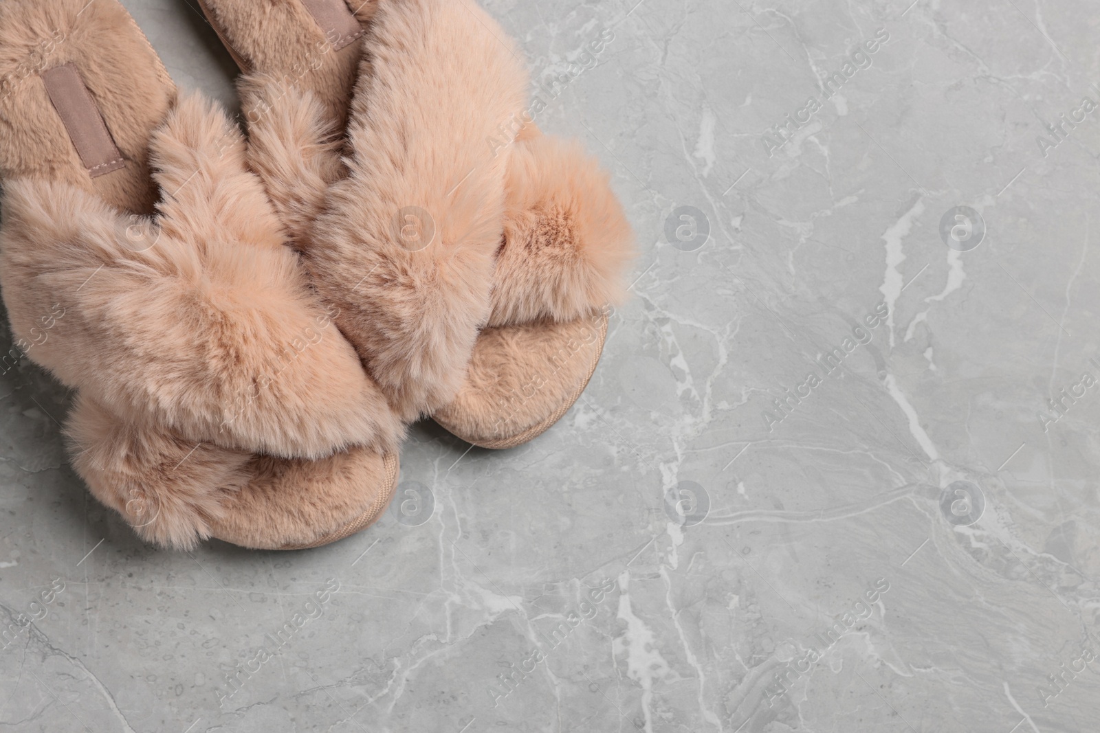 Photo of Pair of soft slippers on grey marble floor, top view. Space for text