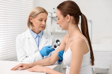 Photo of Dermatologist with dermatoscope examining patient in clinic