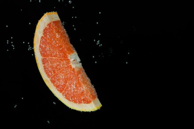 Photo of Slice of grapefruit in sparkling water on black background, space for text. Citrus soda
