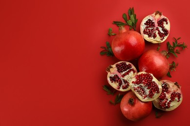 Flat lay composition with ripe pomegranates on red background. Space for text