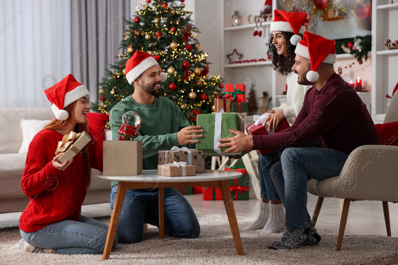 Photo of Christmas celebration. Happy friends in Santa hats exchanging gifts at home