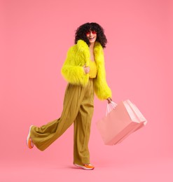 Photo of Happy young woman with shopping bags on pink background. Space for text