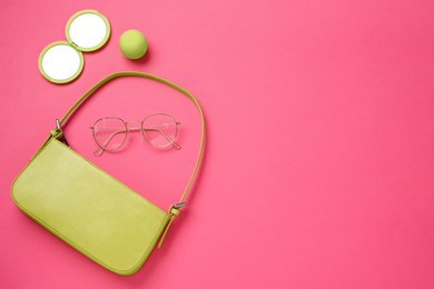 Flat lay composition with stylish baguette handbag on pink background. Space for text