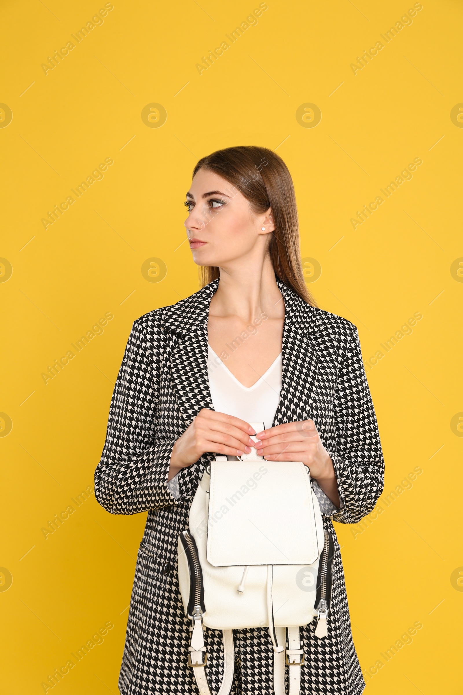 Photo of Beautiful young woman with stylish bag on yellow background