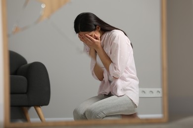 Mental problems. Depressed woman reflecting in broken mirror