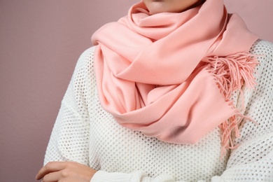 Photo of Woman wearing warm scarf on pink background, closeup. Autumn clothes