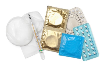 Contraceptive pills, condoms and thermometer isolated on white, top view. Different birth control methods
