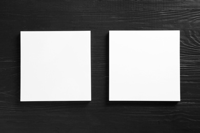 Photo of Blank paper sheets for brochure on black wooden background, flat lay. Mock up