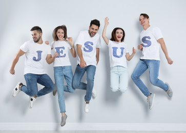 Image of Group of young people wearing T-shirts with letters near light wall. Christian religion