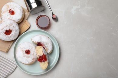 Delicious donuts with jelly and powdered sugar served on light grey table, flat lay. Space for text
