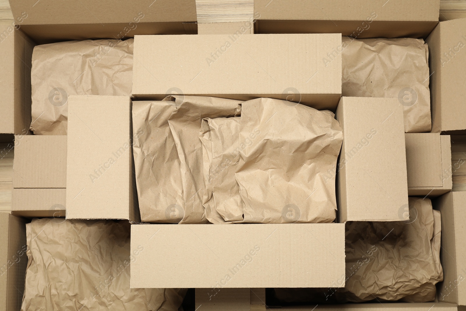 Photo of Many open cardboard boxes with crumpled paper on wooden floor, flat lay