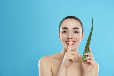 Photo of Young woman with aloe vera leaf on light blue background. Space for text