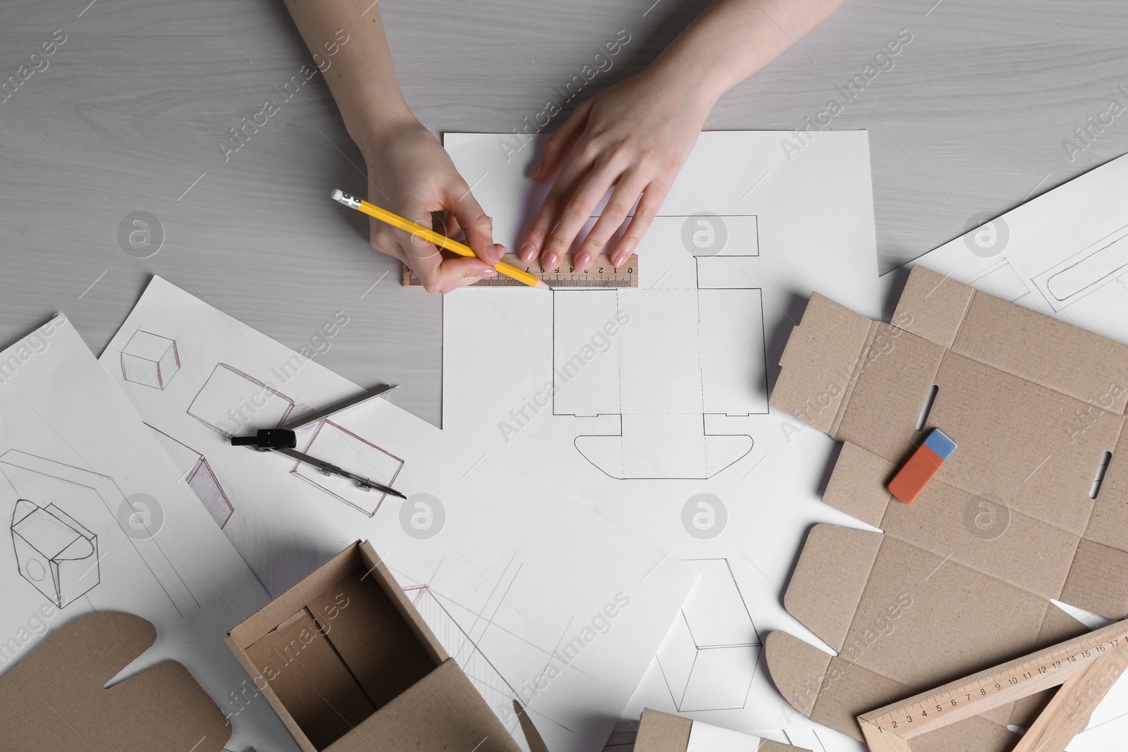 Photo of Woman creating packaging design at light wooden table, top view