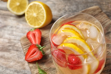 Photo of Natural lemonade with strawberries in glass on table, closeup