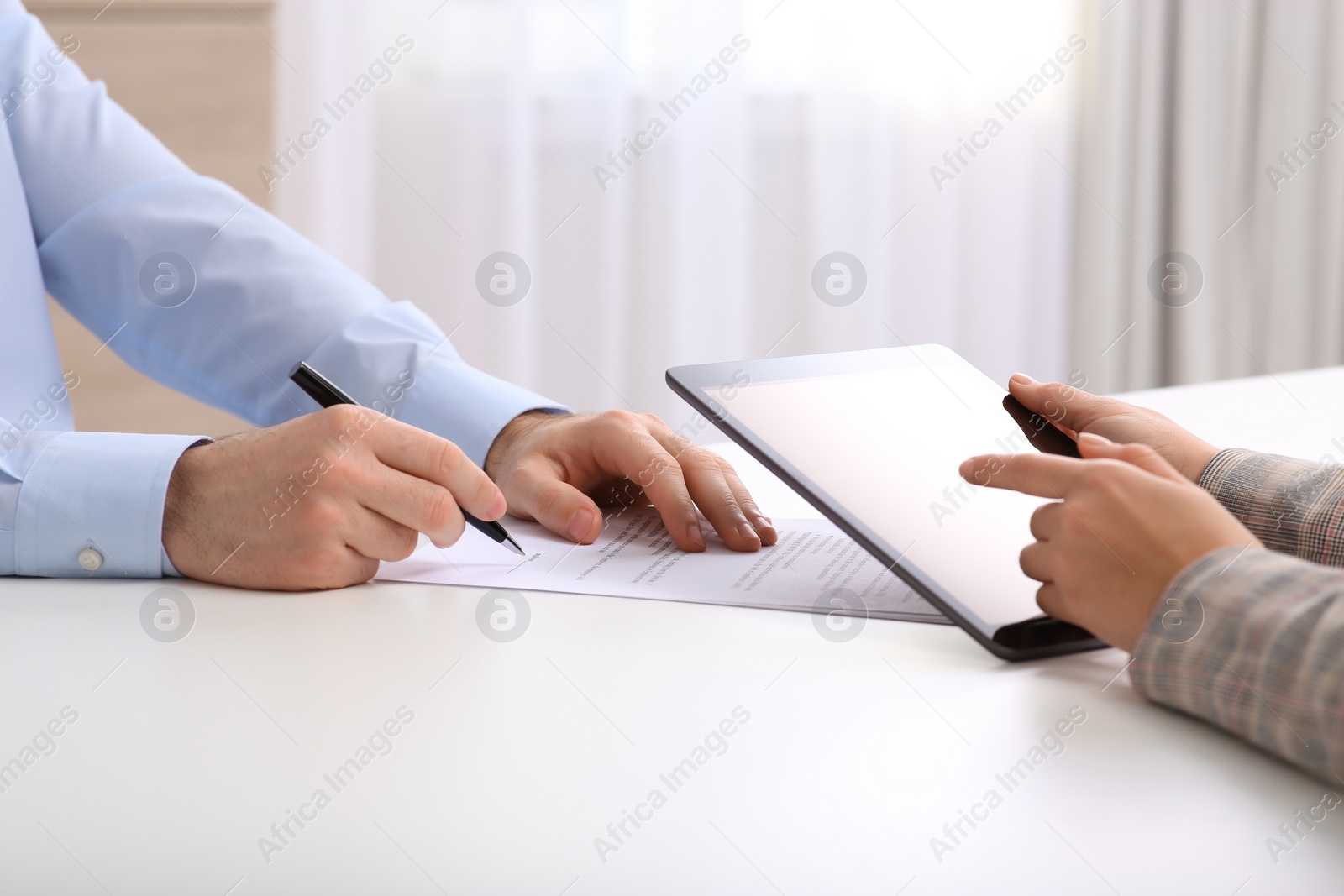 Photo of Businesspeople signing contract at white table in office, closeup of hands