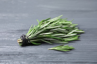 Photo of Bunch of fresh rosemary on color table, space for text