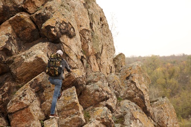 Male hiker with travel backpack climbing up mountain