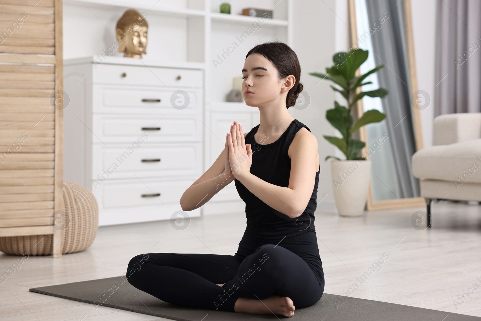 Photo of Beautiful girl meditating on yoga mat at home