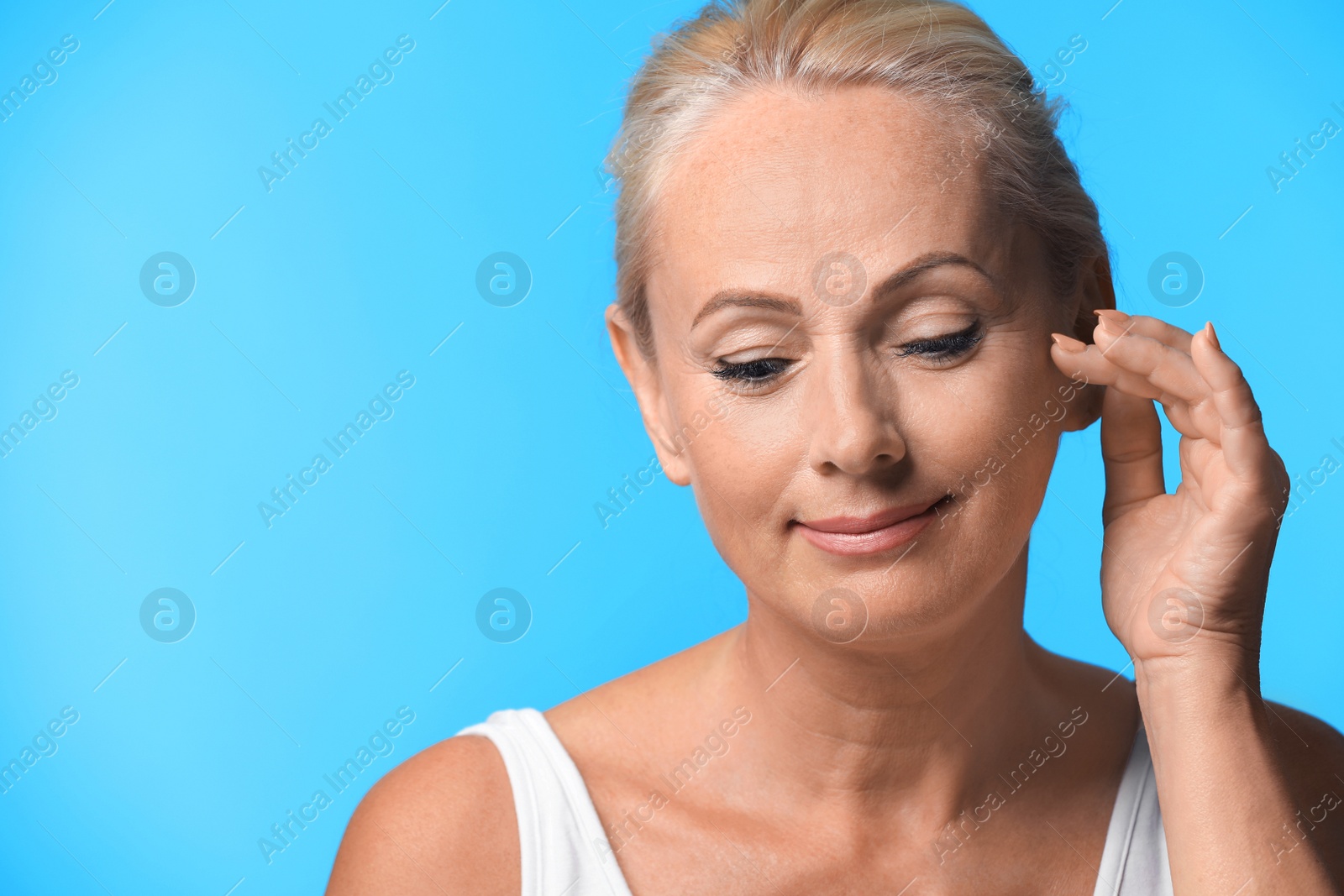Photo of Portrait of beautiful mature woman with perfect skin on light blue background. Space for text